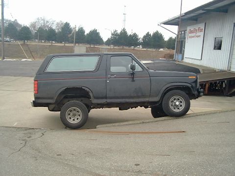 1986 Ford Bronco - This Ford Bronco is parked on a paved surface near a building with a ramp.