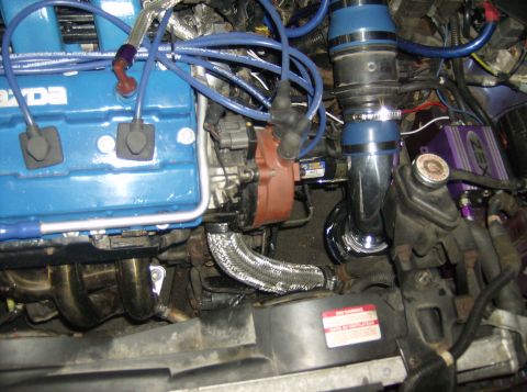 1996 Ford Probe - Close-up view of an engine bay a blue Mazda engine cover, chrome intake piping, and a ZEX nitrous oxide system.