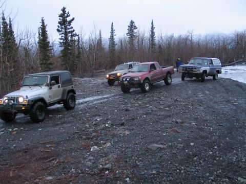2003 Jeep TJ - A group of four-wheel-drive vehicles navigate a rough, gravelly terrain under an overcast sky.