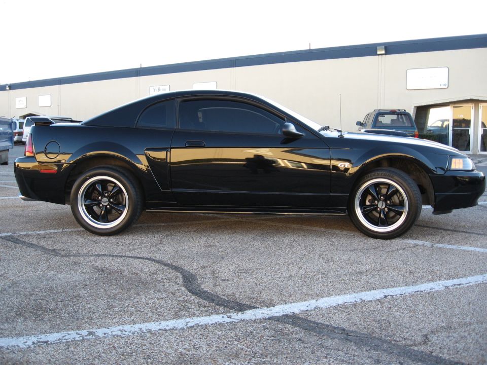 Black Ford Mustang coupe, side view, aftermarket wheels, spoiler, tinted windows