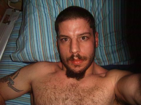 1993 Ford Bronco - A man with a beard and tattoo is seen lying down on a striped surface.
