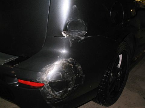 2006 Mazda Mazda 5 - The rear passenger side of a vehicle shows extensive damage, including dents and scrapes on the quarter panel and bumper.