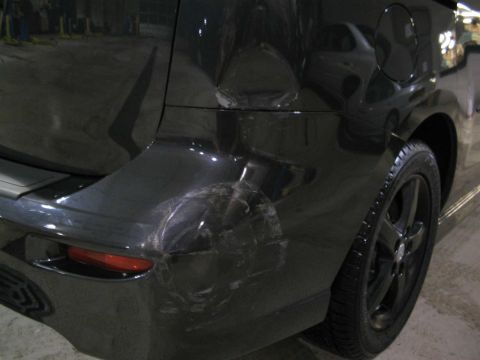 2006 Mazda Mazda 5 - Rear view of a damaged black minivan showing extensive bodywork issues on the bumper and quarter panel.