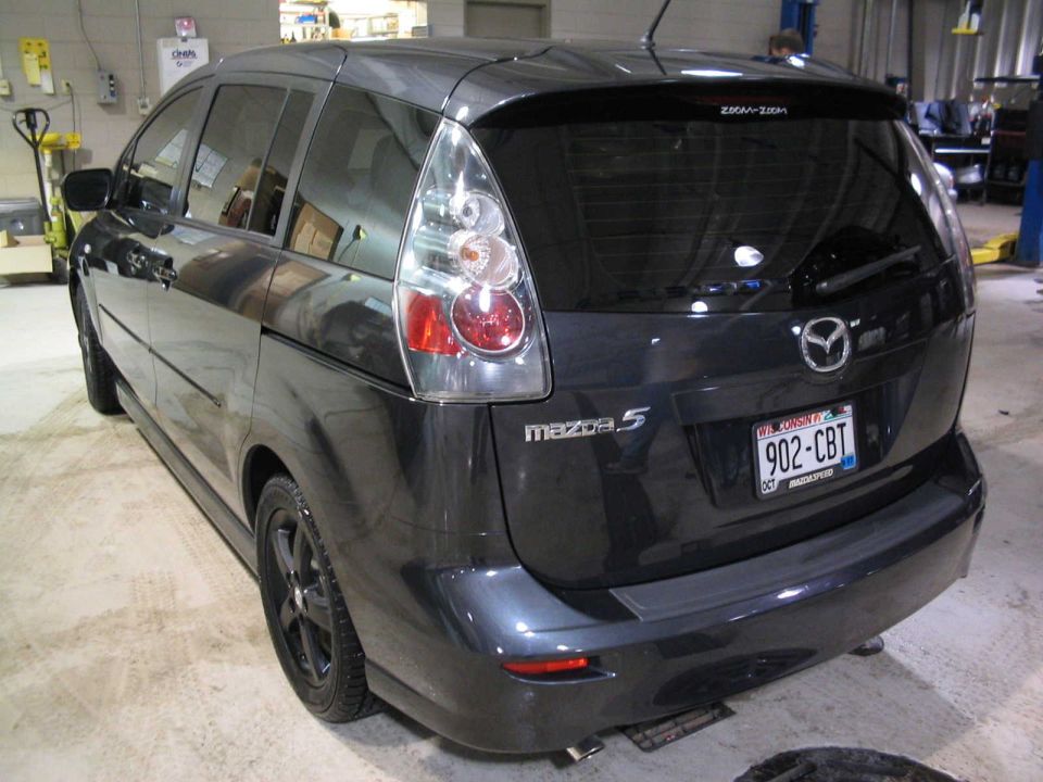 Dark gray Mazda 5 minivan rear three-quarter view in a shop with black alloy wheels