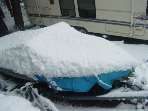 1986 Ford Bronco - A vehicle is covered in a thick blanket of snow, with a blue tarp peeking out from underneath.
