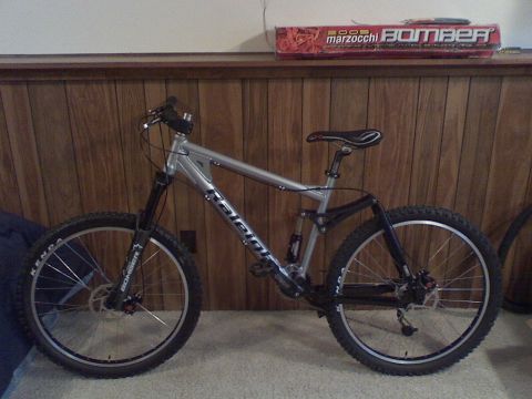 1997 Ford Probe - A silver Raleigh full-suspension mountain bike is shown indoors against a wood-paneled wall.