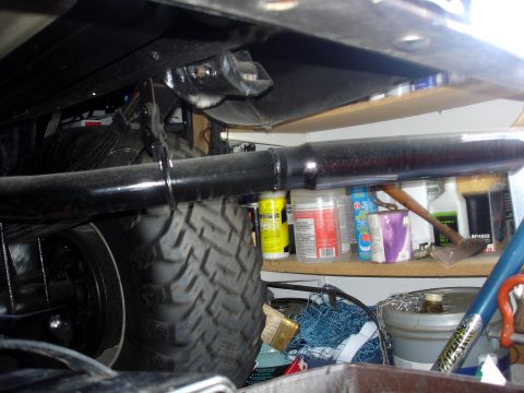 1979 Ford F-250 - Undercarriage view of a vehicle, focusing on the tire and exhaust system, with storage shelves in the background.