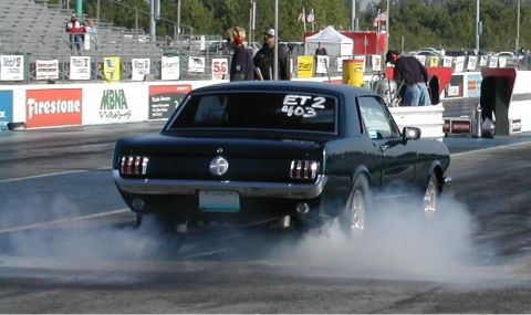 1963 Ford Fairlane - 1965 Ford Mustang performing a burnout on a drag strip, with "ET2 403" written on the rear window.