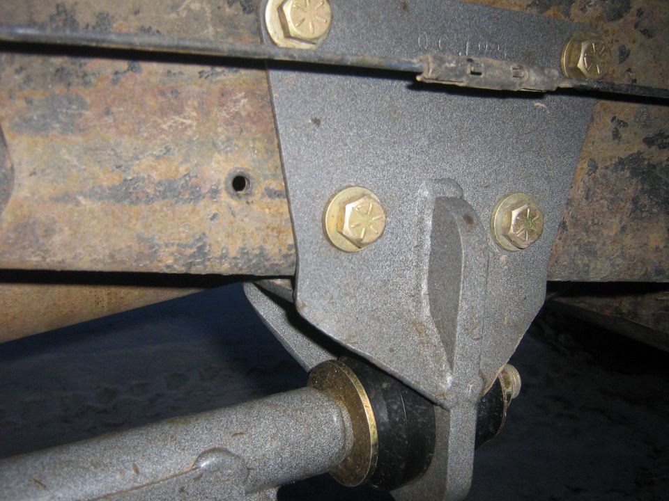 Close-up of a gray suspension bracket with gold bolts and a black bushing