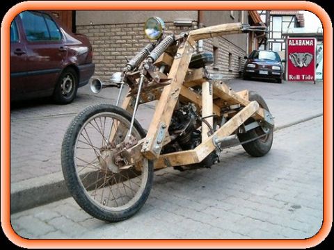 1968 Ford Mustang - A homebuilt chopper-style motorcycle with a frame made from bolted wooden beams, parked on a paver sidewalk beside a brick building. It has…