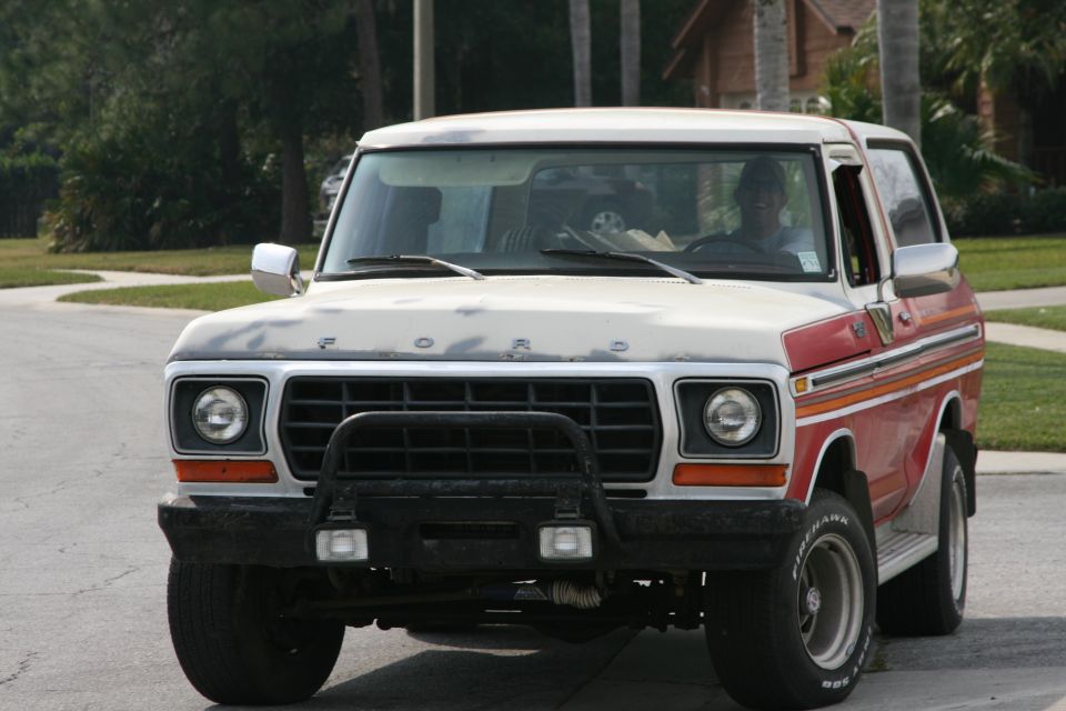 White and red Ford SUV, front 3/4 view, with black brush guard and round headlights on a street