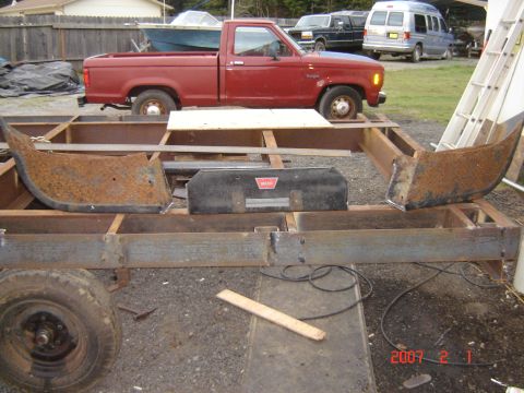 1993 Ford Bronco - Rusty bumper sections and a winch are mounted on a metal frame, with a red pickup truck visible in the background.