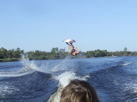 1998 Moomba Boomerang - A wakeboarder performs an aerial trick while being towed by a boat on a sunny day.