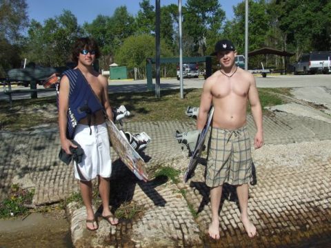 1998 Moomba Boomerang - Two men prepare for watersports, holding wakeboards and life vests in a sunny outdoor setting.