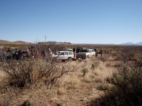 1996 Ford Bronco - A group of people and vehicles are gathered in a desert landscape under a clear blue sky.