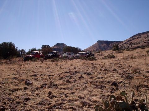 1996 Ford Bronco - A group of off-road vehicles are parked in a dry, hilly landscape on a sunny day.