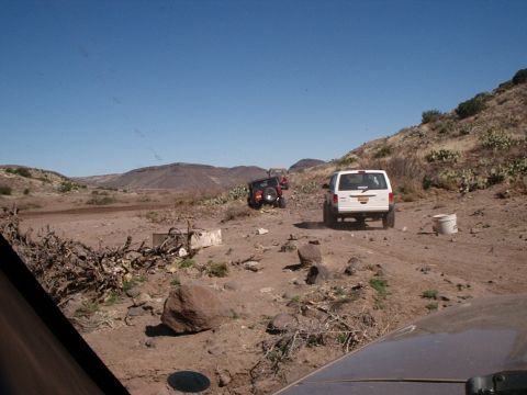 1996 Ford Bronco - Multiple off-road vehicles navigate a dry, arid landscape under a clear blue sky.