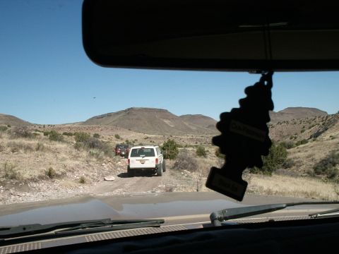 1996 Ford Bronco - A convoy of SUVs navigates a dusty trail through a mountainous, arid landscape under a clear blue sky.