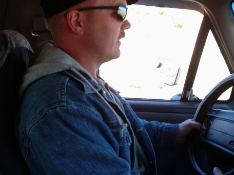 1996 Ford Bronco - A man is driving a vehicle on a sunny day.