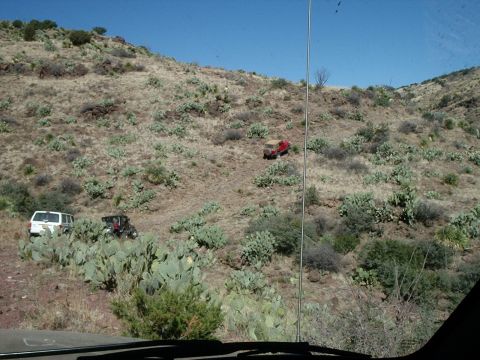 1996 Ford Bronco - Several off-road vehicles navigate a steep, arid hillside dotted with prickly pear cacti under a clear blue sky.