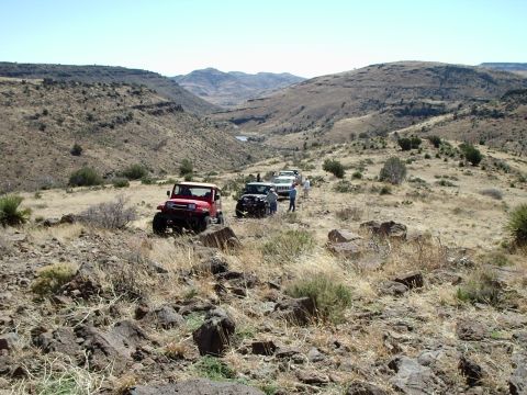 1996 Ford Bronco - Multiple off-road vehicles navigate a challenging rocky trail in a remote, arid environment.