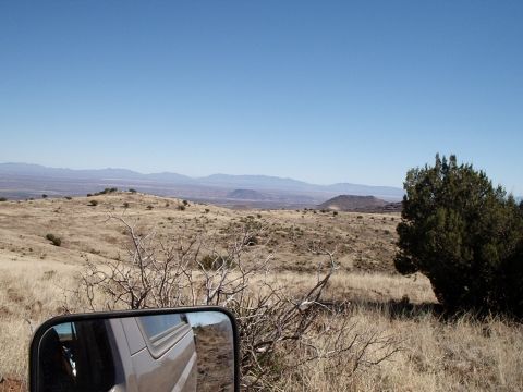1996 Ford Bronco - View from inside a silver SUV driving through a dry, hilly landscape under a clear blue sky.