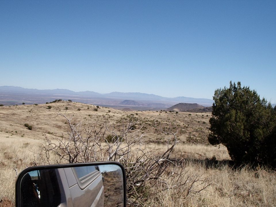 Silver SUV side mirror reflecting landscape