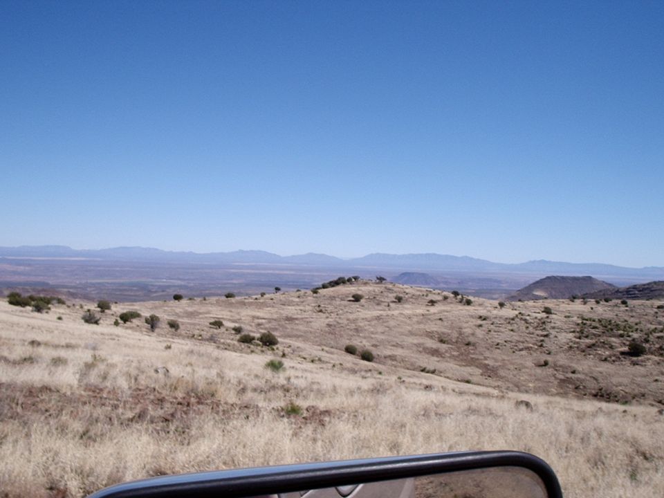 View of dry hills and distant mountains from inside a vehicle