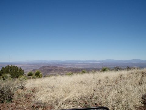 1996 Ford Bronco - A vast, arid landscape unfolds under a clear blue sky, with dry grass and sparse vegetation in the foreground.