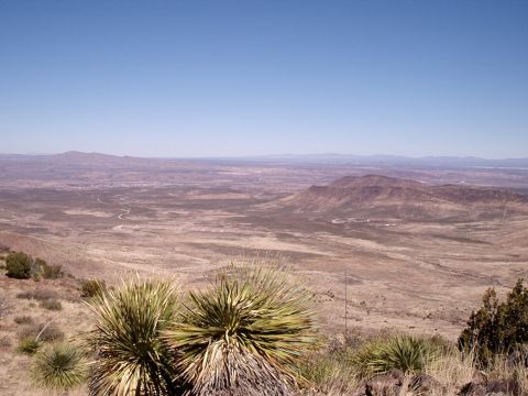 1996 Ford Bronco - Expansive desert vista showing a valley with a winding road and distant mountains under a clear blue sky.