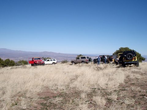 1996 Ford Bronco - Several off-road vehicles gathered on a ridge overlooking a valley under a clear blue sky.