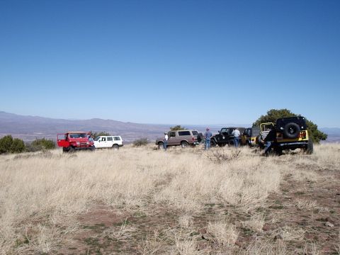 1996 Ford Bronco - A group of off-road vehicles are gathered on a hilltop overlooking a valley on a clear day.