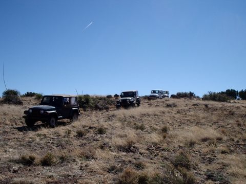 1996 Ford Bronco - Three Jeeps traverse a dry, grassy hillside on a clear day.