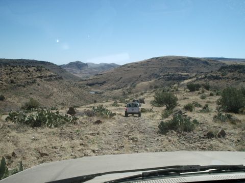 1996 Ford Bronco - Off-road vehicles navigate a challenging trail in a remote desert canyon.
