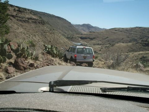 1996 Ford Bronco - A white SUV navigates a desert terrain with mountains in the background.