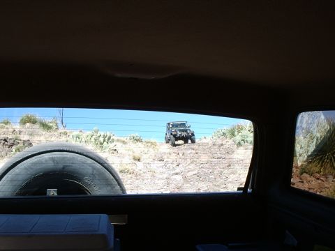 1996 Ford Bronco - A Jeep Wrangler navigates a steep, rocky incline in a desert landscape.