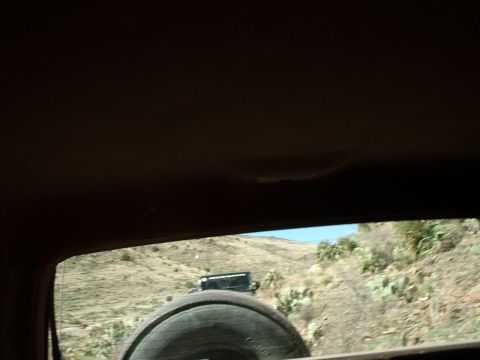 1996 Ford Bronco - Two vehicles travel on a dry, hilly terrain with sparse vegetation under a clear blue sky.