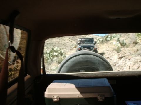1996 Ford Bronco - Two vehicles navigate a dusty, arid trail with sparse vegetation.