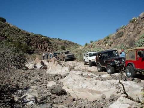 1996 Ford Bronco - A group of 4x4 vehicles navigate a challenging rocky terrain under a clear blue sky.