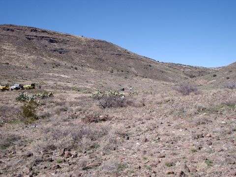 1996 Ford Bronco - Multiple off-road vehicles are parked in a desolate, hilly terrain with sparse vegetation.