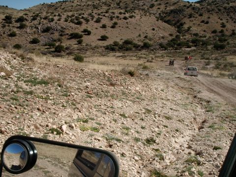 1996 Ford Bronco - Multiple vehicles navigate a rough dirt track in a desolate, arid environment.