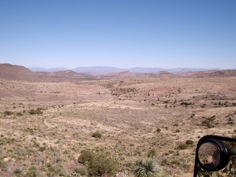 1996 Ford Bronco - A vast desert landscape under a clear blue sky, viewed from a vehicle's side mirror.