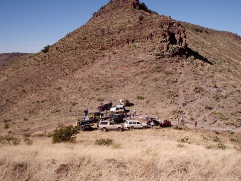 1996 Ford Bronco - Several off-road vehicles are parked together on a barren, rocky slope under a clear blue sky.