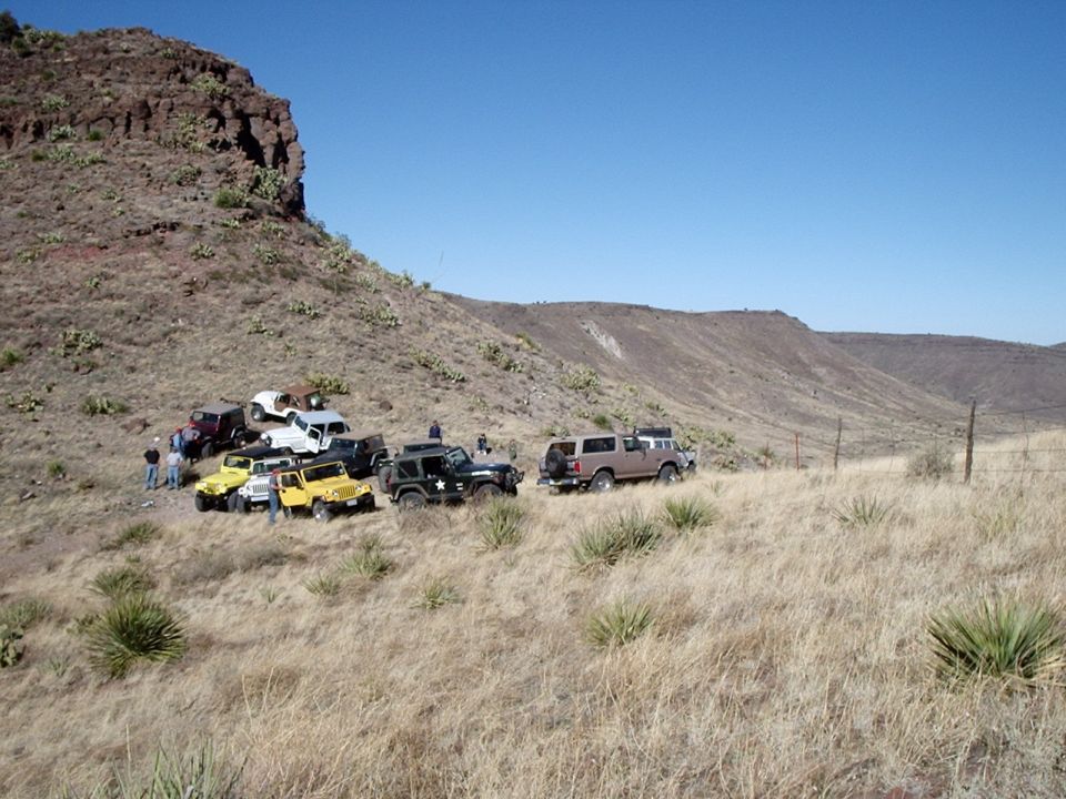 1996 Ford Bronco parked with other off-road vehicles on a dry hillside