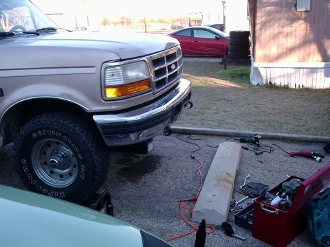 1996 Ford Bronco - A tan Ford truck is parked outside with tools scattered on the ground nearby.