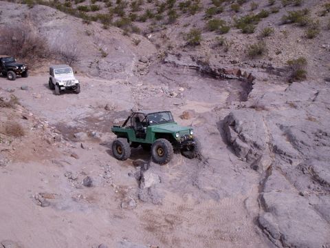 1996 Ford Bronco - Multiple off-road vehicles traverse a rocky, arid landscape.