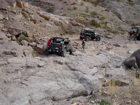 1996 Ford Bronco - Several off-road vehicles navigate a challenging rocky trail under a bright sky.
