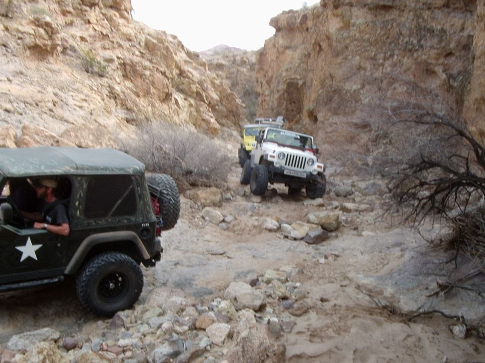 Several Jeeps navigate a , rocky canyon trail