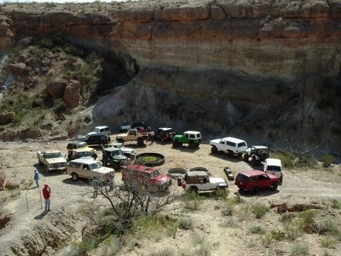 1996 Ford Bronco - A group of off-road vehicles, including a tan 1996 Ford Bronco, are gathered in a scenic canyon area.