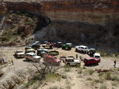 1996 Ford Bronco - Many off-road vehicles are gathered in a desert canyon, with a group of people standing in the center.